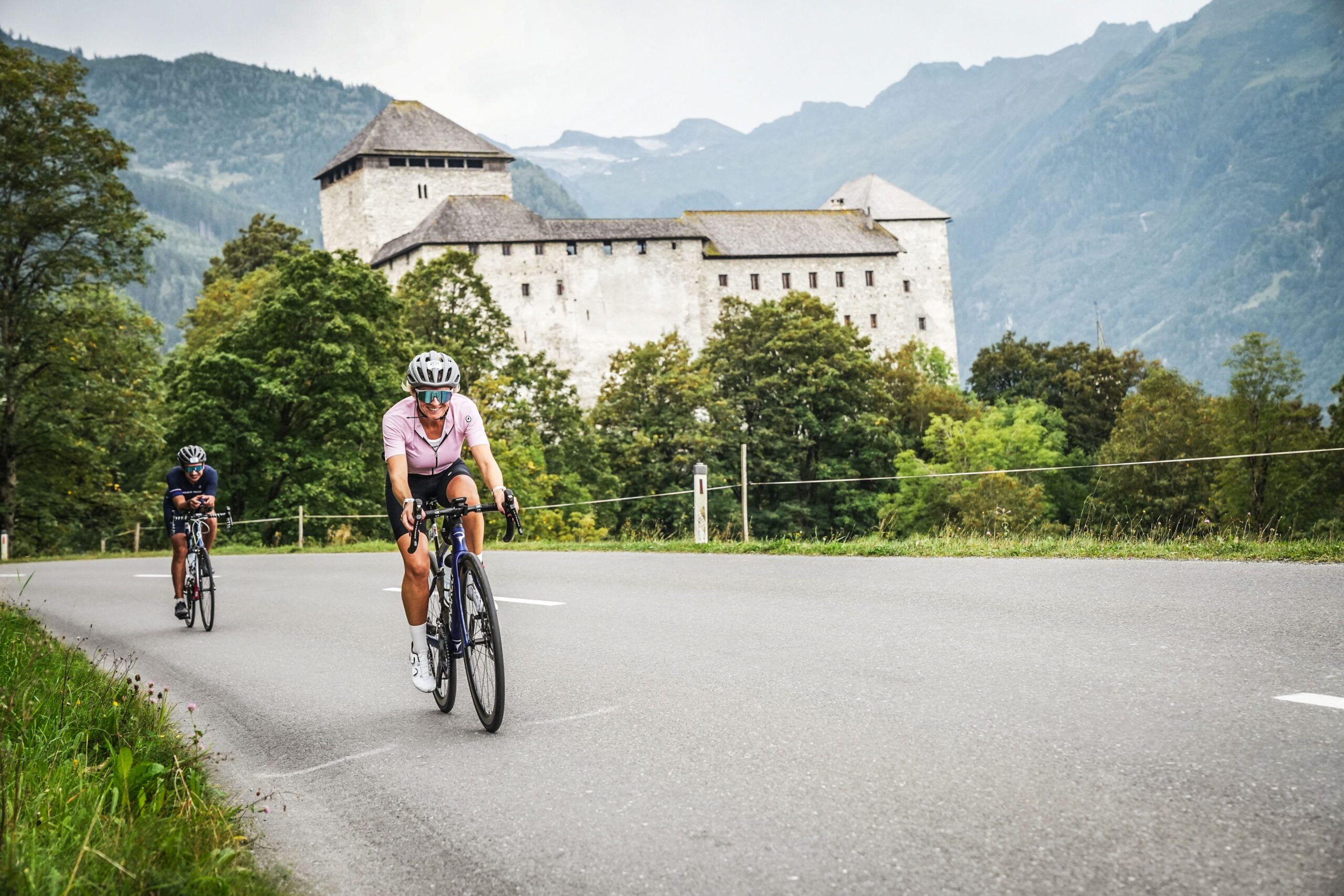 Michaela rides her bike through the Ironman on a road with a castle in the background